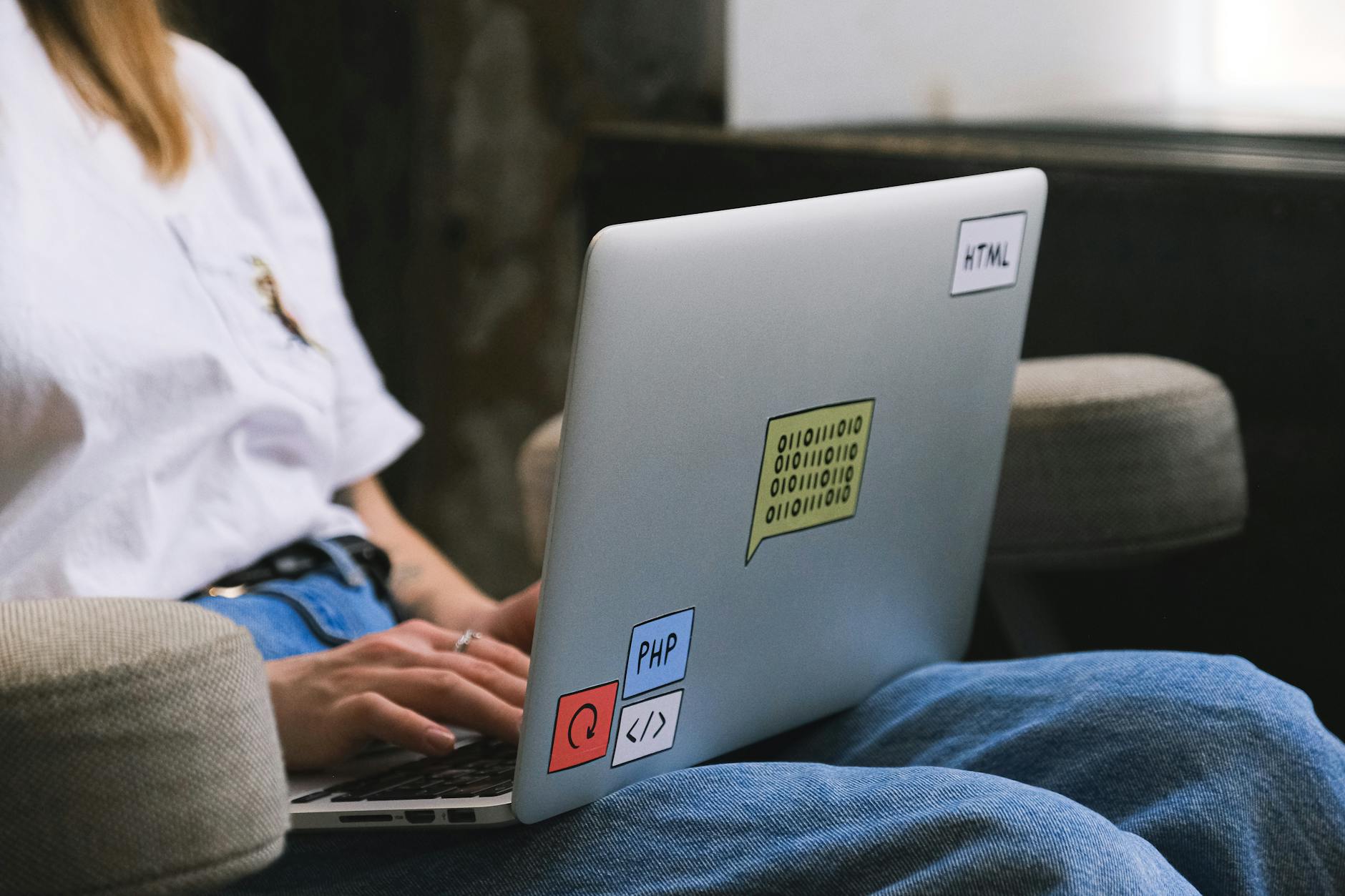 Programista piszący na laptopie z naklejkami, pracujący zdalnie