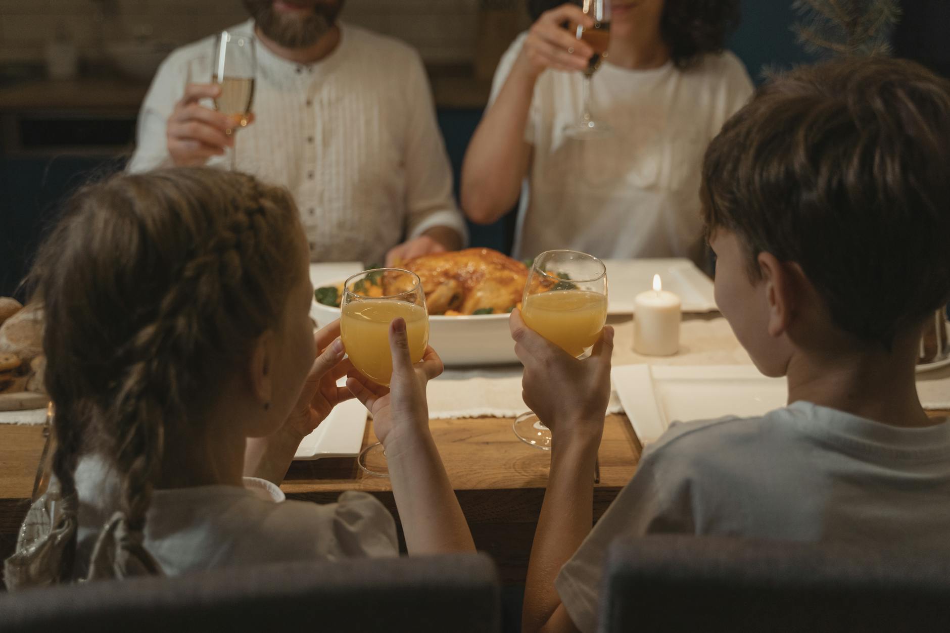 Rodzinna kolacja w Meksyku, dzieci i dorośli wznoszą toast przy stole